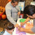 a man helping the girl creating halloween crafts
