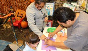 a man helping the girl creating halloween crafts