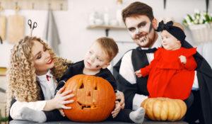 a family wearin Halloween costumes and holding a carved pumpkin