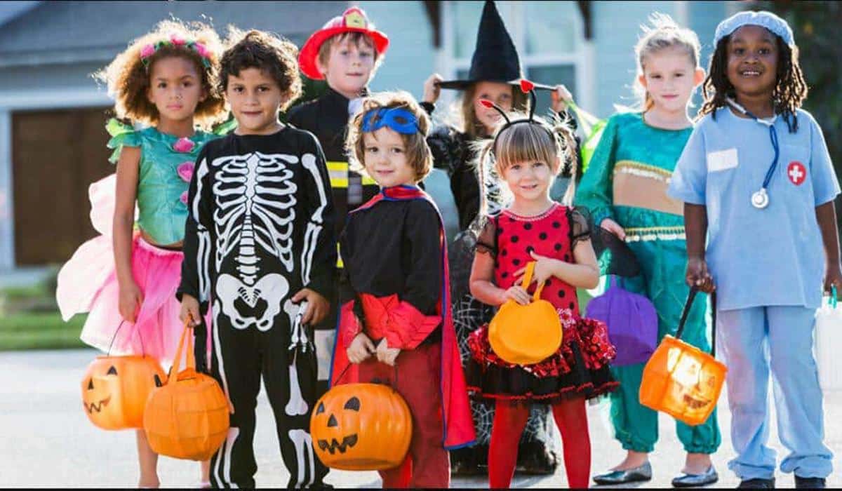 a group of kids on the street wearing Halloween costumes