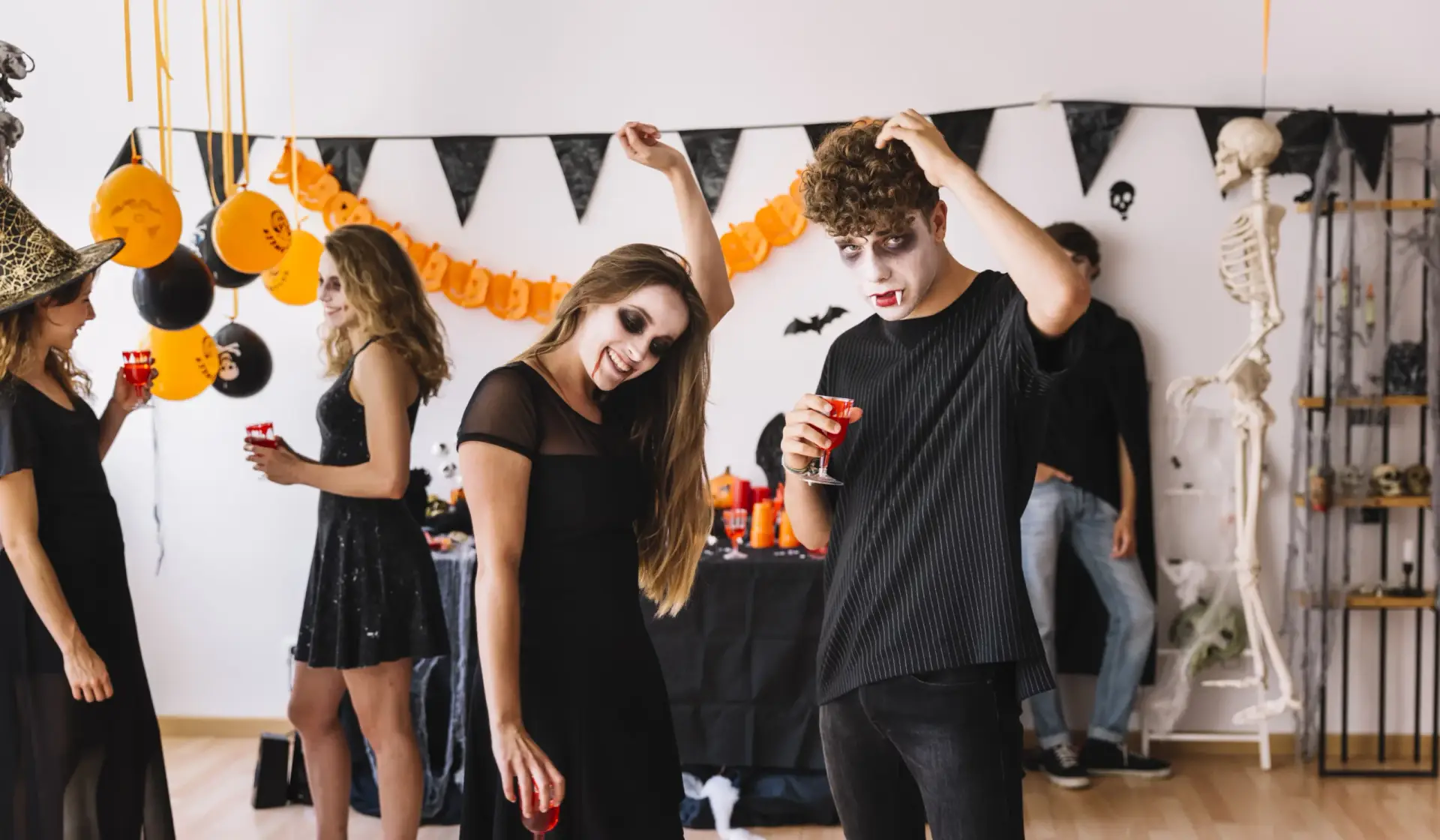 Teens enjoying Halloween dance games in costumes, with vampire makeup and festive decorations in the background.